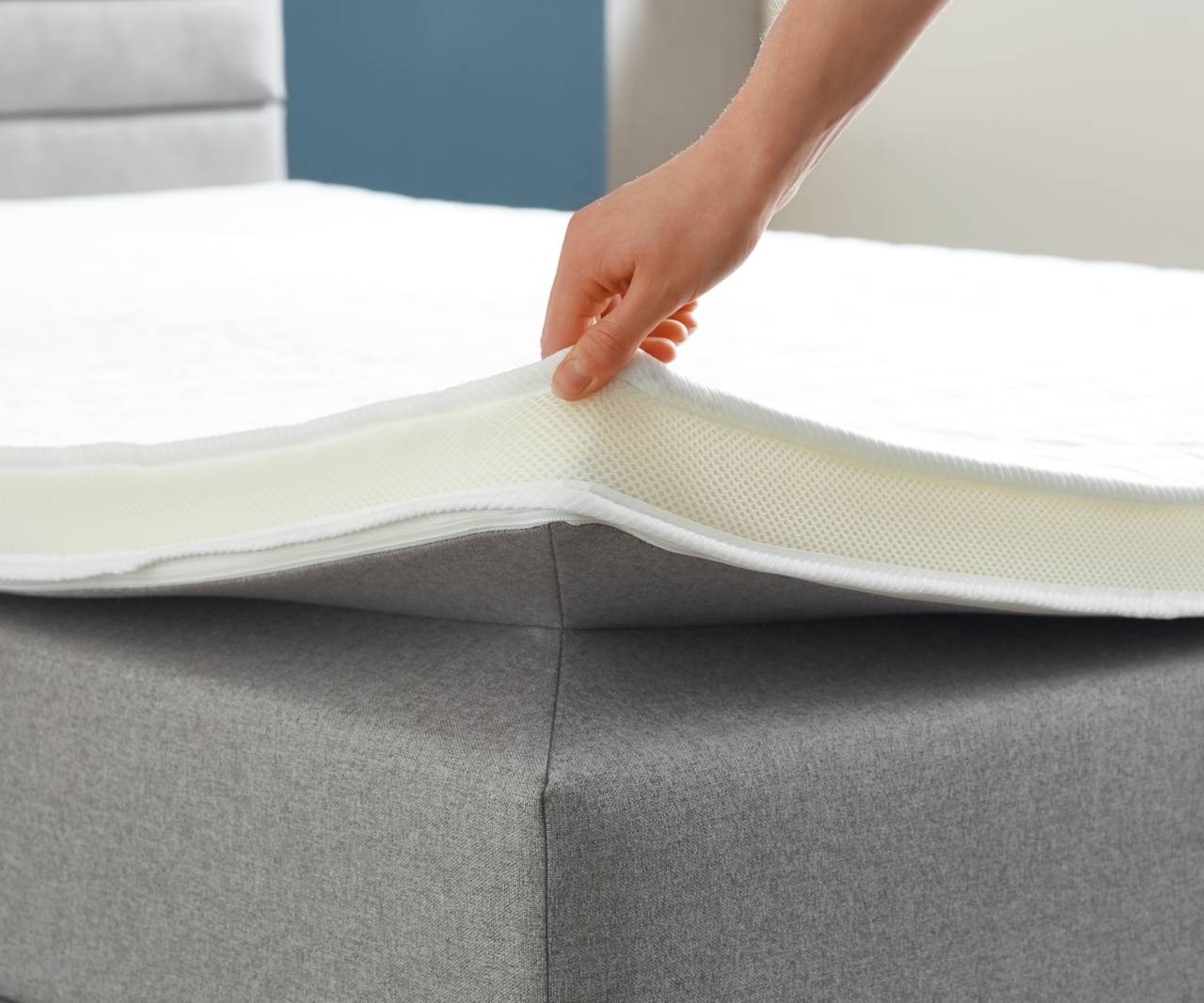 Nahaufnahme eines Boxspringbetts mit einer Hand, die die Matratze anhebt, um die Schichten zu zeigen.