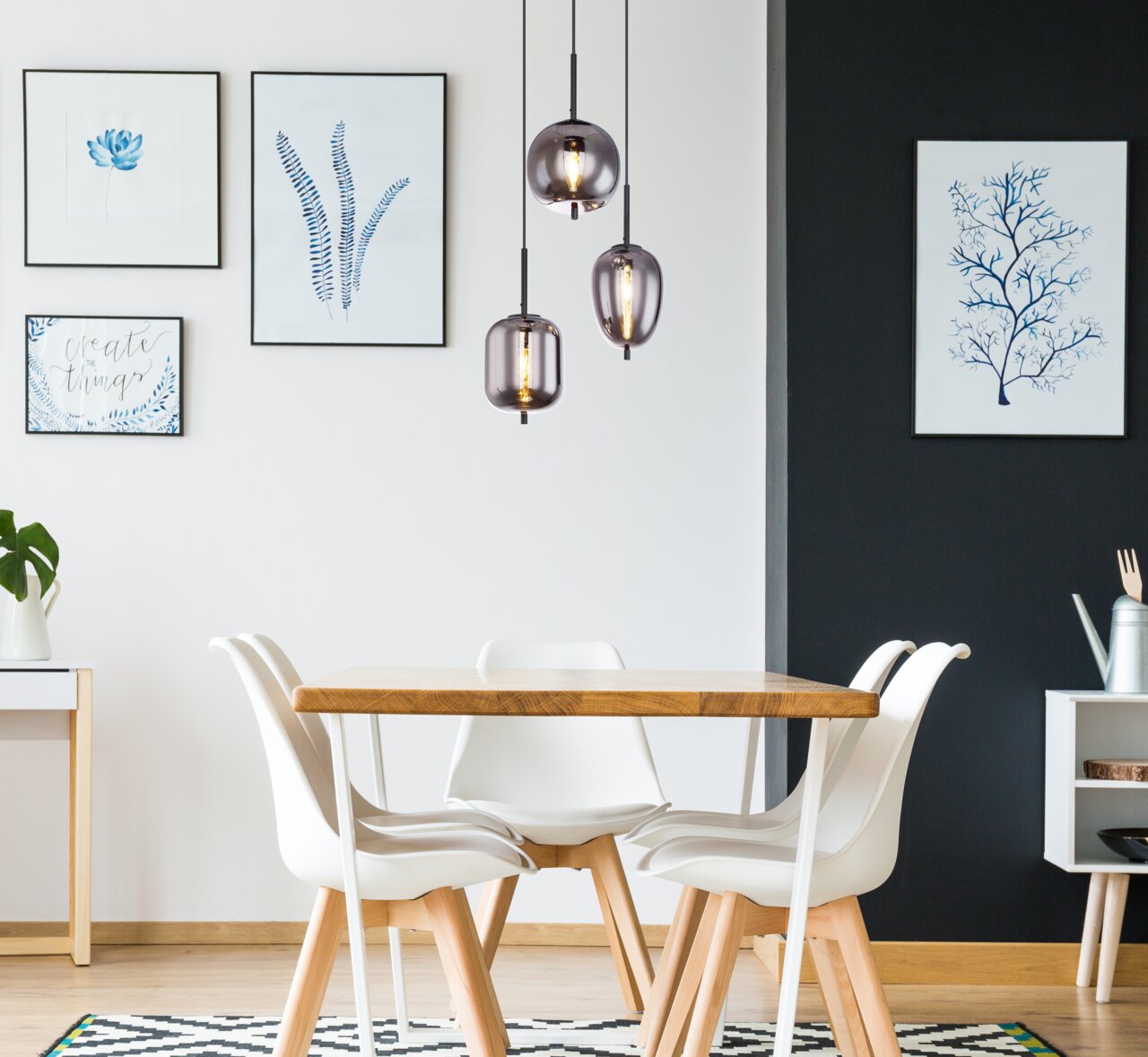 Moderne hanglamp BLACKY met drie rookgrijze glazen bollen, hangend boven een eettafel in een stijlvol ingerichte ruimte, gezien vanaf de zijkant.