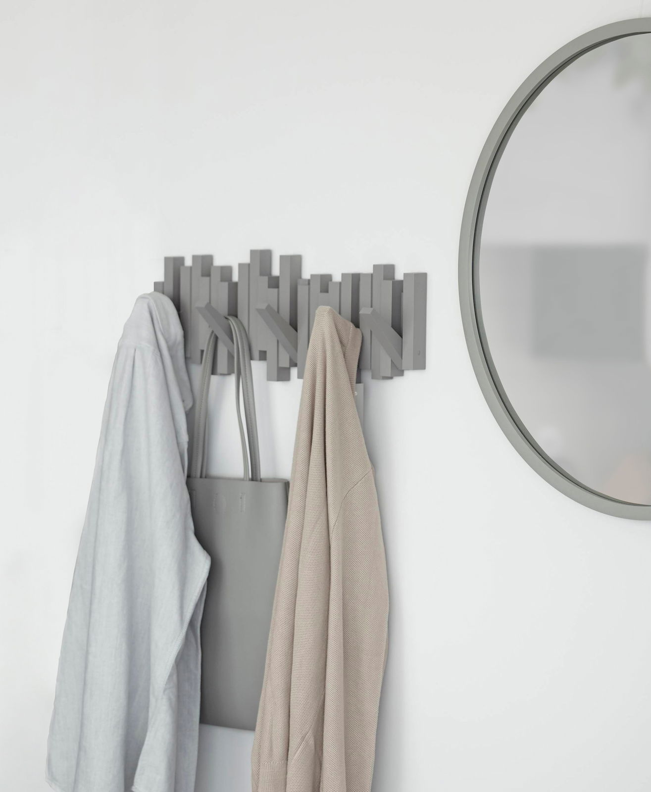 Moderne Wandgarderobe mit mehreren Haken, an der Kleidung und eine Tasche hängen. Perspektive von vorne.