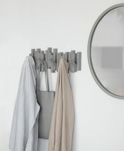 Moderne Wandgarderobe mit mehreren Haken, an der Kleidung und eine Tasche hängen. Perspektive von vorne.