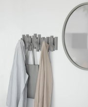 Moderne Wandgarderobe mit mehreren Haken, an der Kleidung und eine Tasche hängen. Perspektive von vorne.