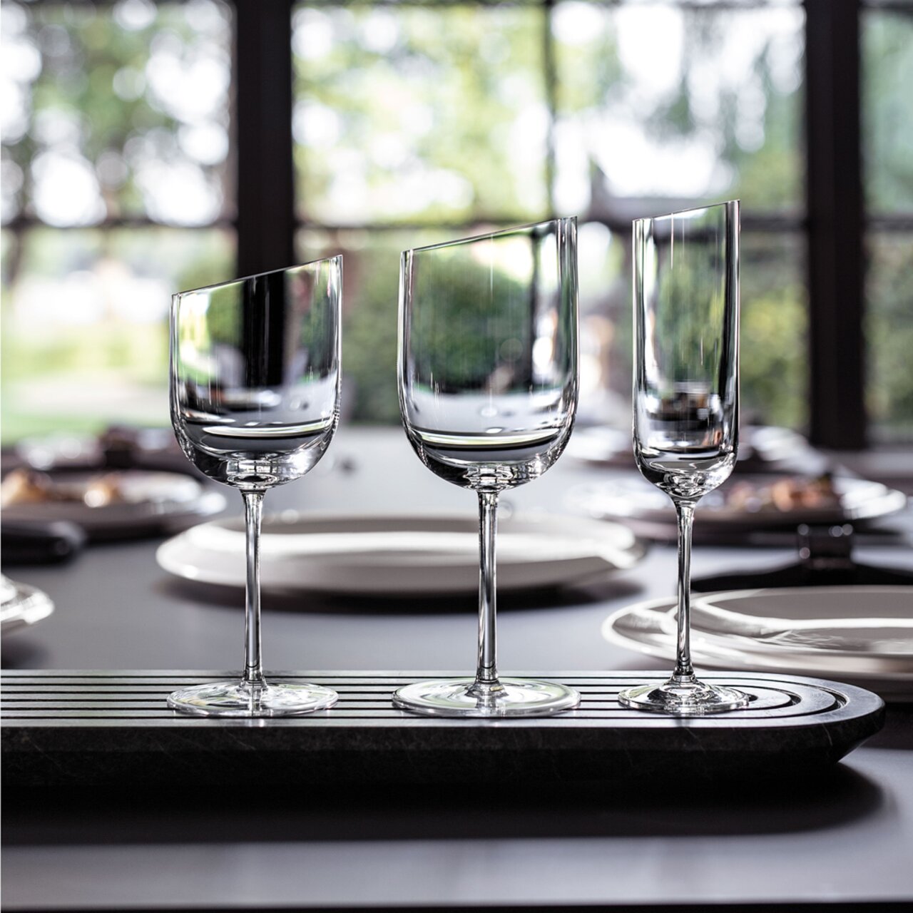 Drie elegante rodewijnglazen in een modern ontwerp op een tafel, gezien vanaf de zijkant.
