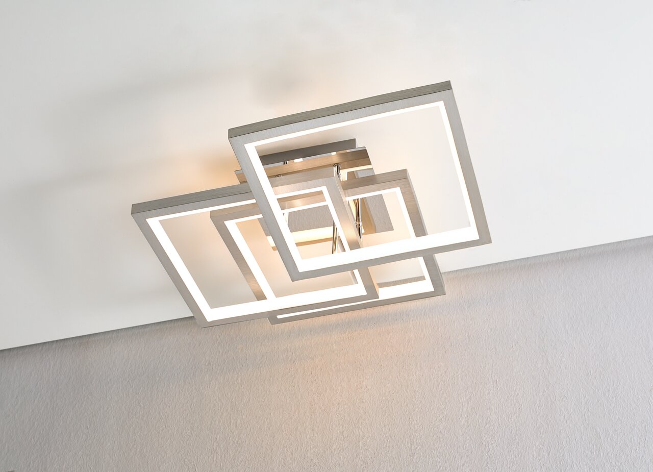 Moderne led-plafondlamp met overlappende vierkante randen in metaallook, met een warmwitte lichtkleur, gefotografeerd vanaf de onderkant van het plafond.