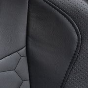 Nahaufnahme der schwarzen Lederpolsterung eines Gaming Stuhls mit perforierten und glatten Bereichen.