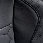 Nahaufnahme der schwarzen Lederpolsterung eines Gaming Stuhls mit perforierten und glatten Bereichen.