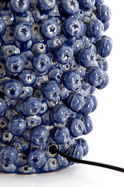 Nahaufnahme eines blauen, strukturierten Lampenfußes mit runden, glänzenden Erhebungen und einem Kabel, das aus der Seite herausragt.