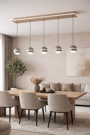 Moderne LED-Pendelleuchte mit fünf kugelförmigen Lampen, hängend über einem Esstisch in einem stilvoll eingerichteten Wohnzimmer, seitliche Perspektive.