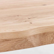 Nahaufnahme einer Tischkante aus hellem Holz mit natürlicher Maserung, seitliche Perspektive