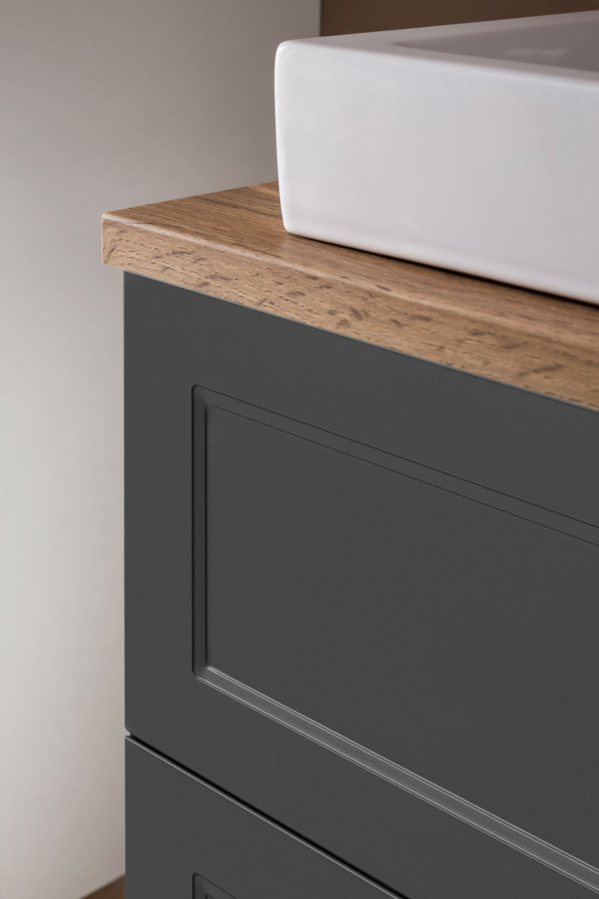 Nahaufnahme eines Waschtisch-Sets mit weißem Waschbecken und dunklem Unterschrank mit Holzoberfläche, seitliche Perspektive.