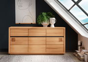 Holz-Sideboard mit sechs Schubladen, dekoriert mit einer Pflanze und einer Vase, vor einer dunklen Wand und einem Dachfenster, aus frontaler Perspektive.