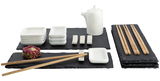 Sushi-Set mit Schieferplatten, weißen Keramikschalen, Essstäbchen und einer Teekanne, aus der Vogelperspektive fotografiert.