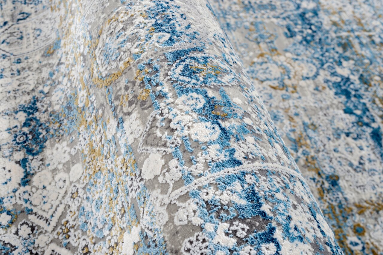 Nahaufnahme eines Designer-Teppichs mit blau-grauen und gelben Mustern, seitliche Perspektive