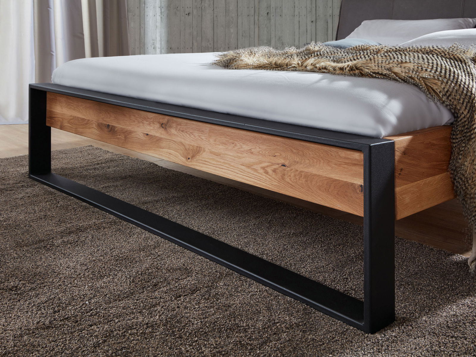 Balkenbett aus Holz mit schwarzem Metallrahmen, seitliche Perspektive