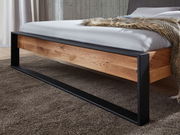 Balkenbett aus Holz mit schwarzem Metallrahmen, seitliche Perspektive