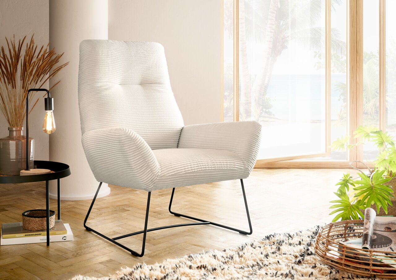 Lounge Handmade Sessel LH-BEN Moderner cremefarbener Sessel mit geripptem Stoffbezug und schwarzen Metallbeinen, seitliche Perspektive in einem hellen Raum mit großen Fenstern.