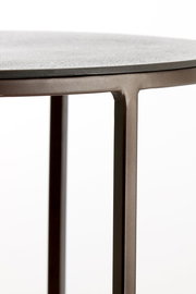 Nahaufnahme eines Beistelltisches mit runder Tischplatte und schlanken Metallbeinen, seitliche Perspektive.