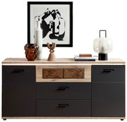 Moderne Kommode/Sideboard in Holzoptik mit mattschwarzen Fronten und Schubladen, dekoriert mit Vase, Glasobjekt, Skulptur, Büchern, Tischlampe und gerahmter Grafik; frontale Ansicht.