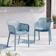 Zwei hellblaue Outdoor-Stühle aus Kunststoff mit geschlitzter Rückenlehne und passenden Sitzkissen auf einer sonnigen Terrasse vor weißer Wand und Pflanzkasten, Frontansicht in leichter Schrägperspektive.