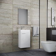 Modernes Badezimmer mit wandhängendem weißem Waschtischunterschrank und Aufsatzwaschbecken, verchromter Armatur und rechteckigem Spiegel an beiger Steinfliesenwand; seitliche Frontansicht aus leicht schräger Perspektive.