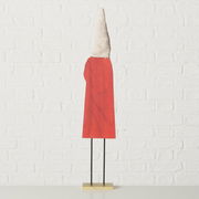 Figur mit rotem Umhang und spitzem, strukturiertem Hut, von hinten betrachtet, auf einem Sockel stehend.