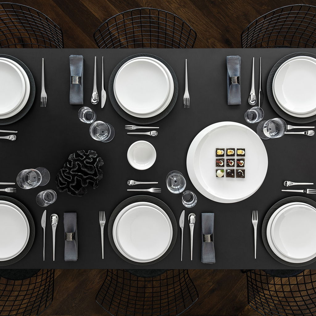Elegante Tischdekoration mit Frühstückstellern und Besteck, aus der Vogelperspektive fotografiert.