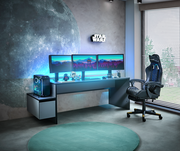 Gaming-Setup mit großem Schreibtisch, drei Monitoren, Gaming-Stuhl und Towerunit, seitliche Perspektive