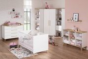 Modernes Kinderzimmer mit weißem Kinderbett aus Holz, umgeben von stilvollen Möbeln in einem hellen Raum mit rosa Akzenten, aus der Perspektive von vorne.