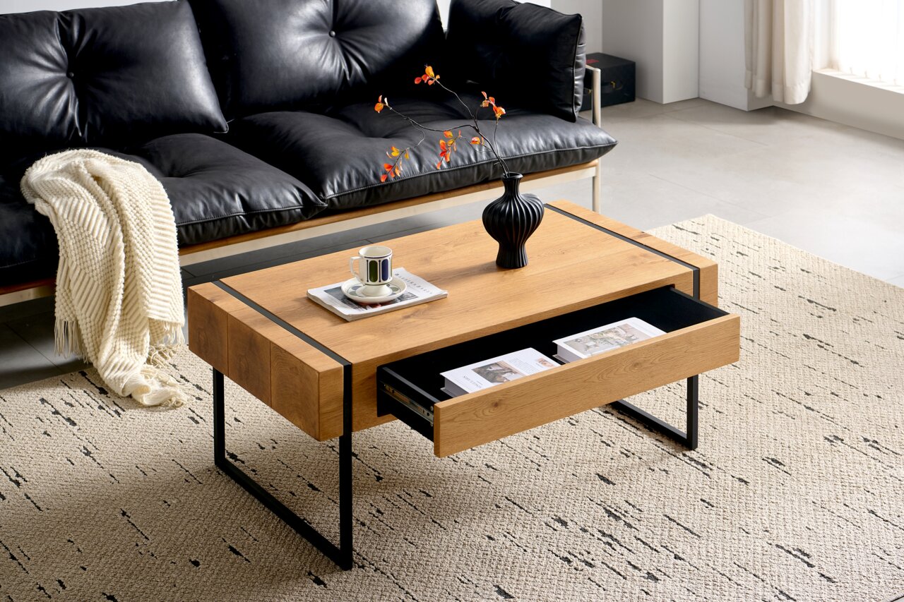 Moderner Couchtisch aus Holz mit schwarzem Metallgestell, Schublade geöffnet, von schräg oben fotografiert, dekoriert mit Vase und Tasse.