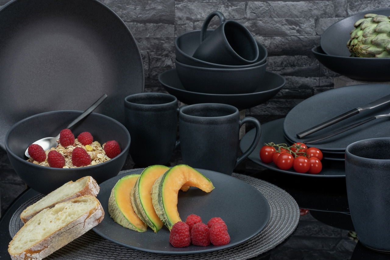 Kombiservice Soft Touch 20-tlg in dunklem Design, bestehend aus Tellern, Schalen und Tassen, präsentiert mit frischen Früchten und Brot auf einem Tisch aus der Vogelperspektive.