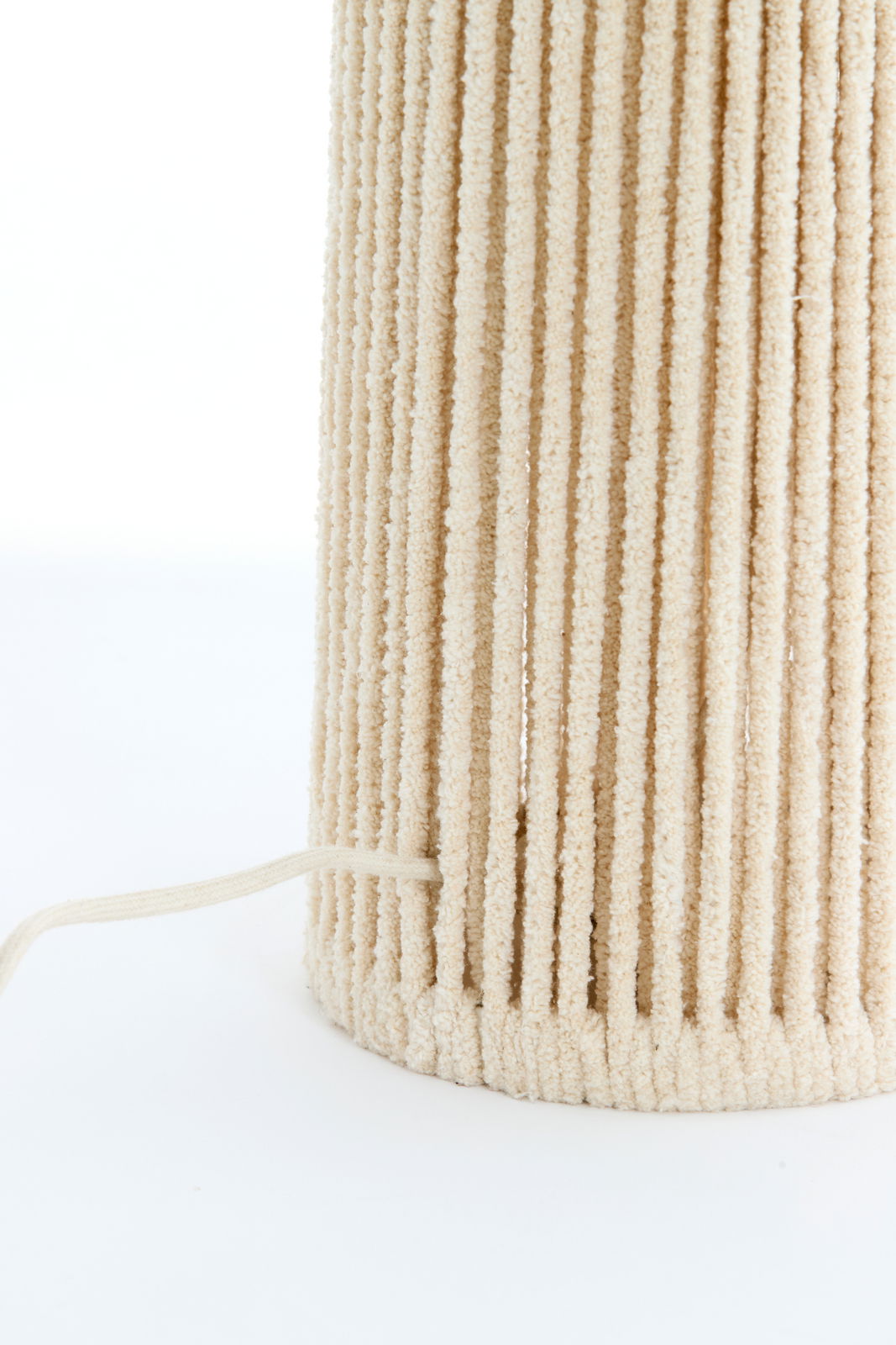 Nahaufnahme einer Stehleuchte mit cremefarbenem, texturiertem Stoffbezug und sichtbarem Kabel.