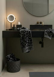 Luxuriöses Handtuch mit Leopardenmuster und JOOP!-Logo, drapiert über einem modernen Waschbecken in einem stilvollen Badezimmer, seitliche Perspektive.