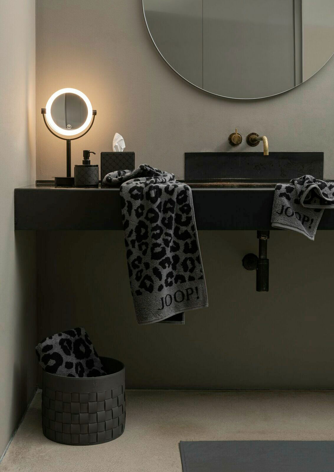Luxuriöses Handtuch mit Leopardenmuster und JOOP!-Logo, drapiert über einem modernen Waschbecken in einem stilvollen Badezimmer, seitliche Perspektive.