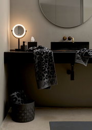 Luxuriöses Handtuch mit Leopardenmuster und JOOP!-Logo, drapiert über einem modernen Waschbecken in einem stilvollen Badezimmer, seitliche Perspektive.