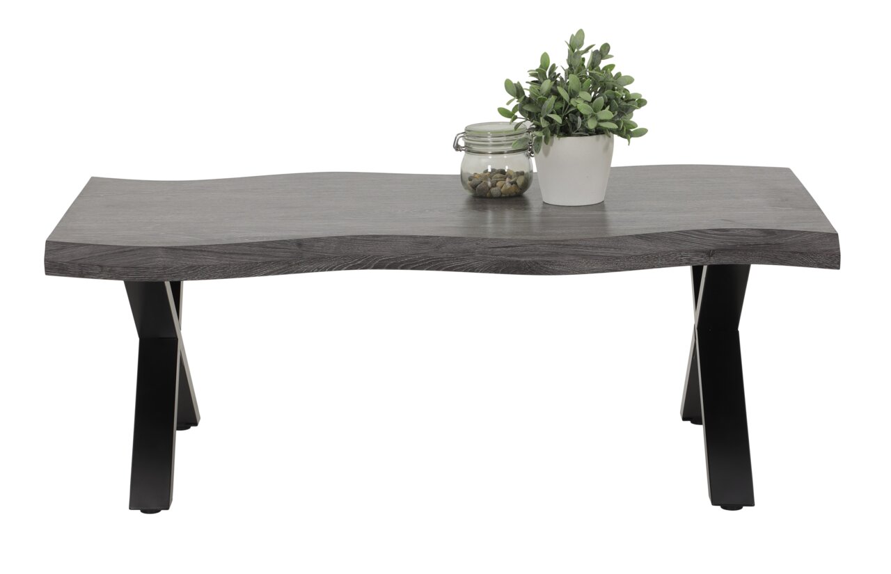 Moderner Couchtisch mit wellenförmiger grauer Tischplatte und schwarzen Metallbeinen, frontal fotografiert. Dekoriert mit einer Pflanze und einem Glasgefäß.