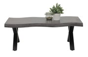 Moderner Couchtisch mit wellenförmiger grauer Tischplatte und schwarzen Metallbeinen, frontal fotografiert. Dekoriert mit einer Pflanze und einem Glasgefäß.