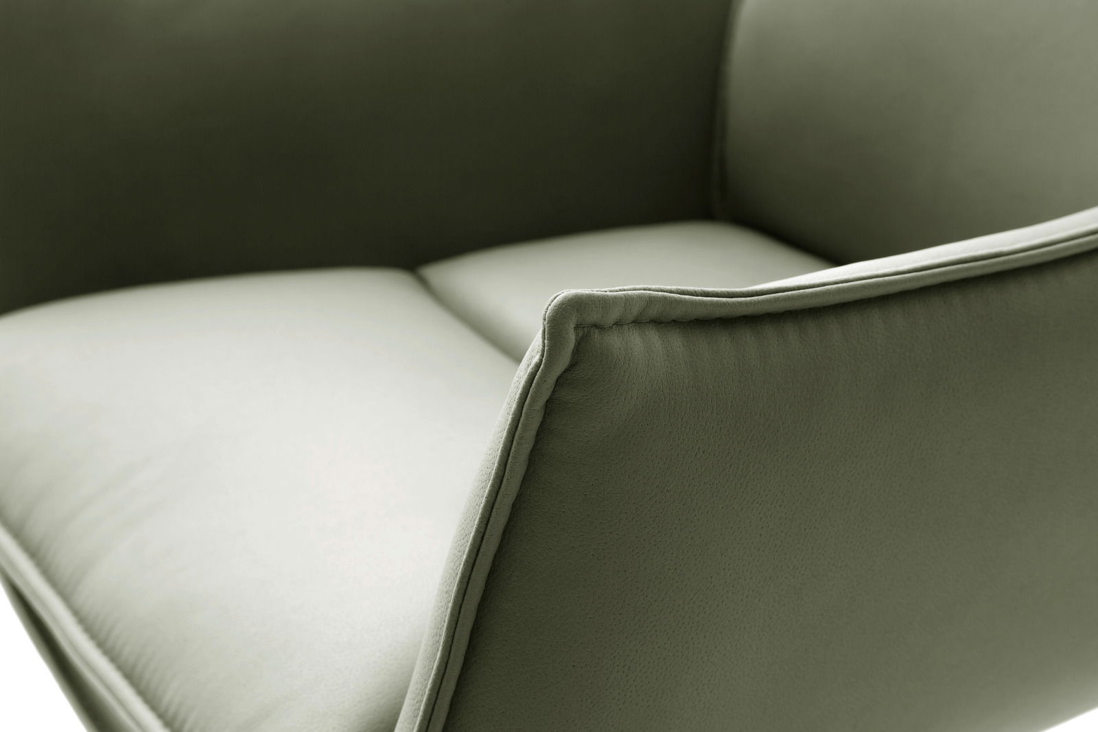 Nahaufnahme eines grünen Sessels mit weicher Polsterung und eleganten Nähten, seitliche Perspektive