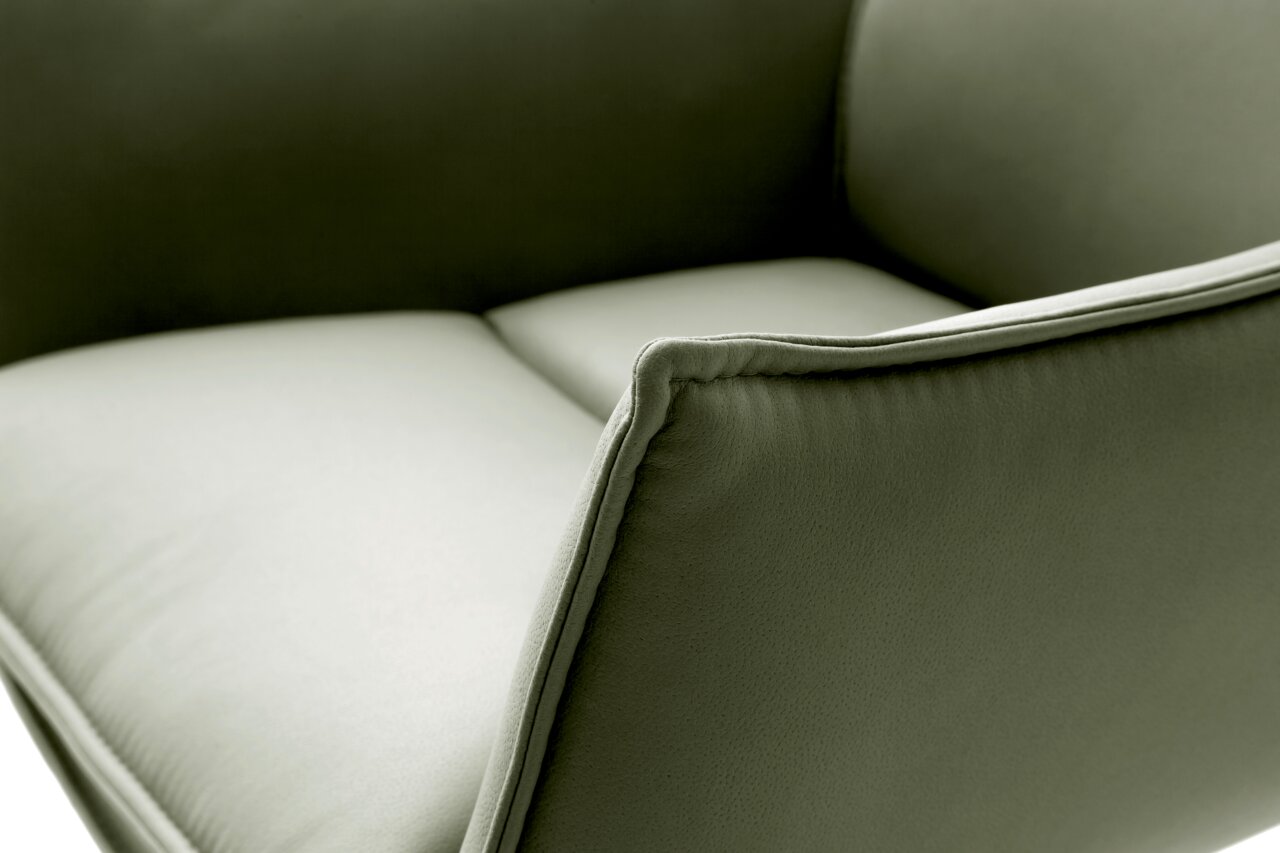 Nahaufnahme eines grünen Sessels mit weicher Polsterung und eleganten Nähten, seitliche Perspektive