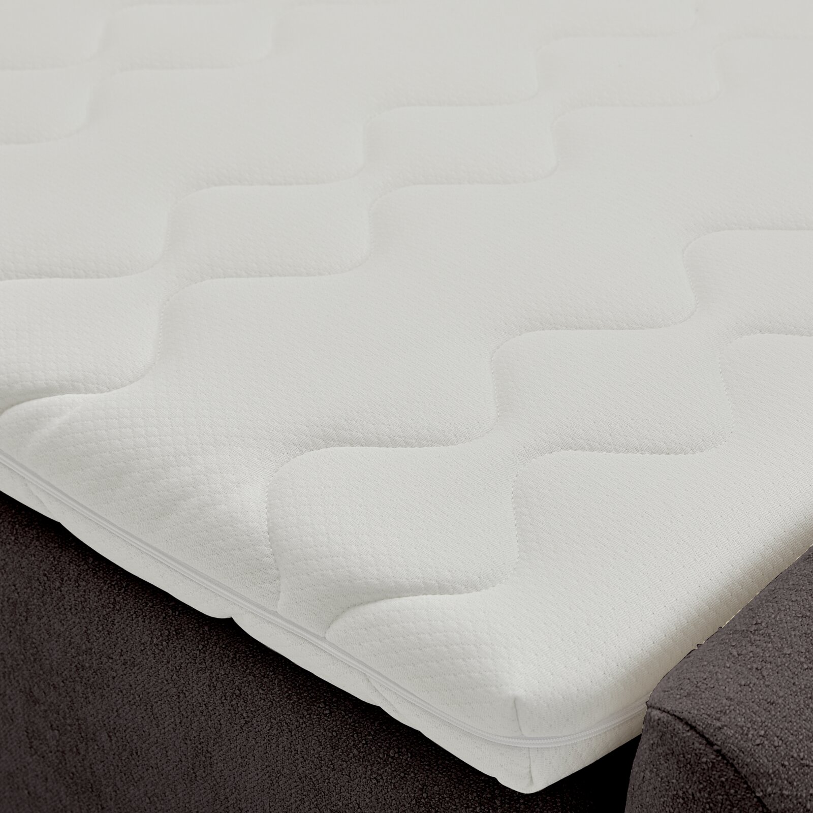 Nahaufnahme eines Boxbetts mit weißem, strukturiertem Topper, seitliche Perspektive
