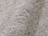 Nahaufnahme eines handgewebten Teppichs in Grautönen, der eine detaillierte Ansicht der Textur und Webart zeigt.