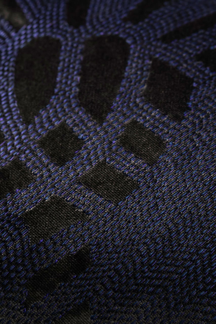 Nahaufnahme einer Zierkissenhülle mit schwarzem und blauem geometrischem Muster.