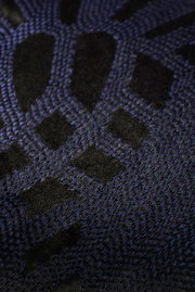 Close-up van een sierkussenhoes met een zwart en blauw geometrisch patroon.