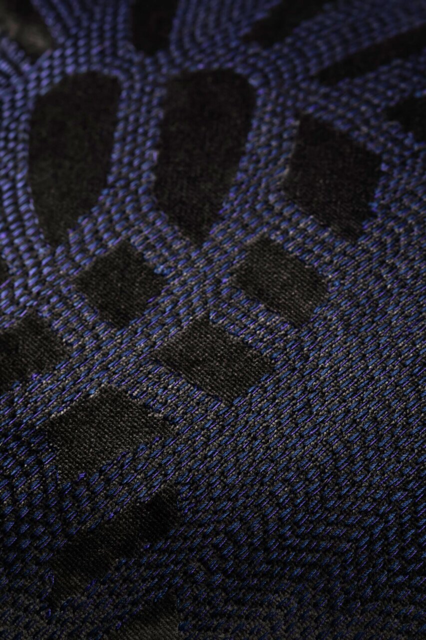 Close-up van een sierkussenhoes met een zwart en blauw geometrisch patroon.