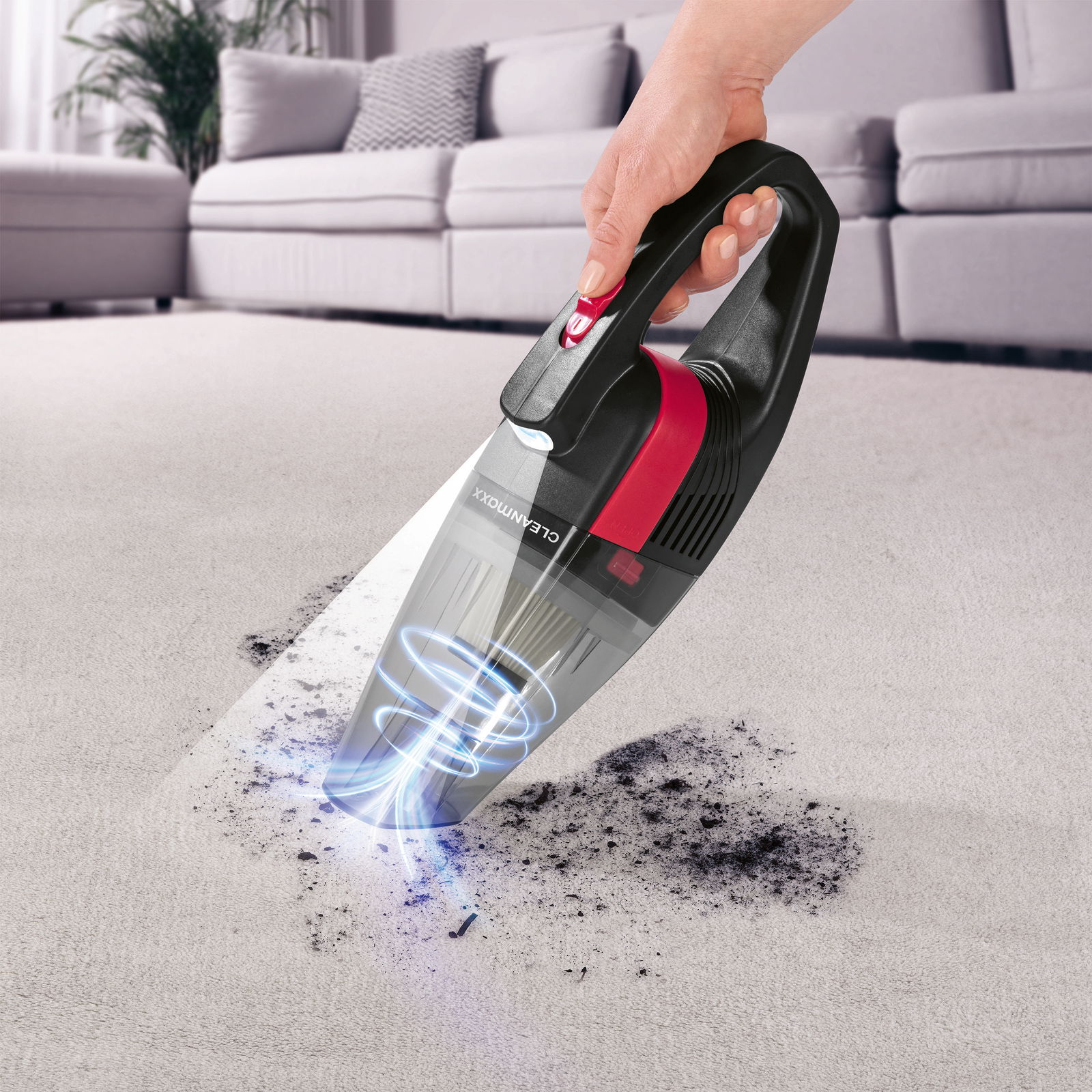 Akku Handstaubsauger in Aktion, der Schmutz von einem Teppich aufsaugt, seitliche Perspektive