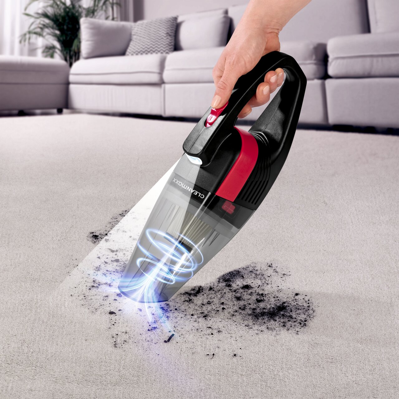Akku Handstaubsauger in Aktion, der Schmutz von einem Teppich aufsaugt, seitliche Perspektive