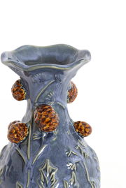 Detailansicht einer blauen Vase mit floralen Verzierungen und erhabenen, braunen Elementen auf der Oberfläche.