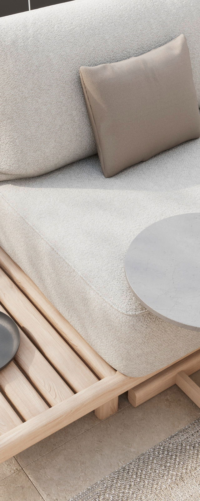 Detailansicht einer Loungeeckgarnitur mit hellem Stoffbezug, beigem Kissen und Holzelementen, von schräg oben fotografiert.