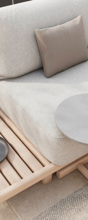 Detailansicht einer Loungeeckgarnitur mit hellem Stoffbezug, beigem Kissen und Holzelementen, von schräg oben fotografiert.
