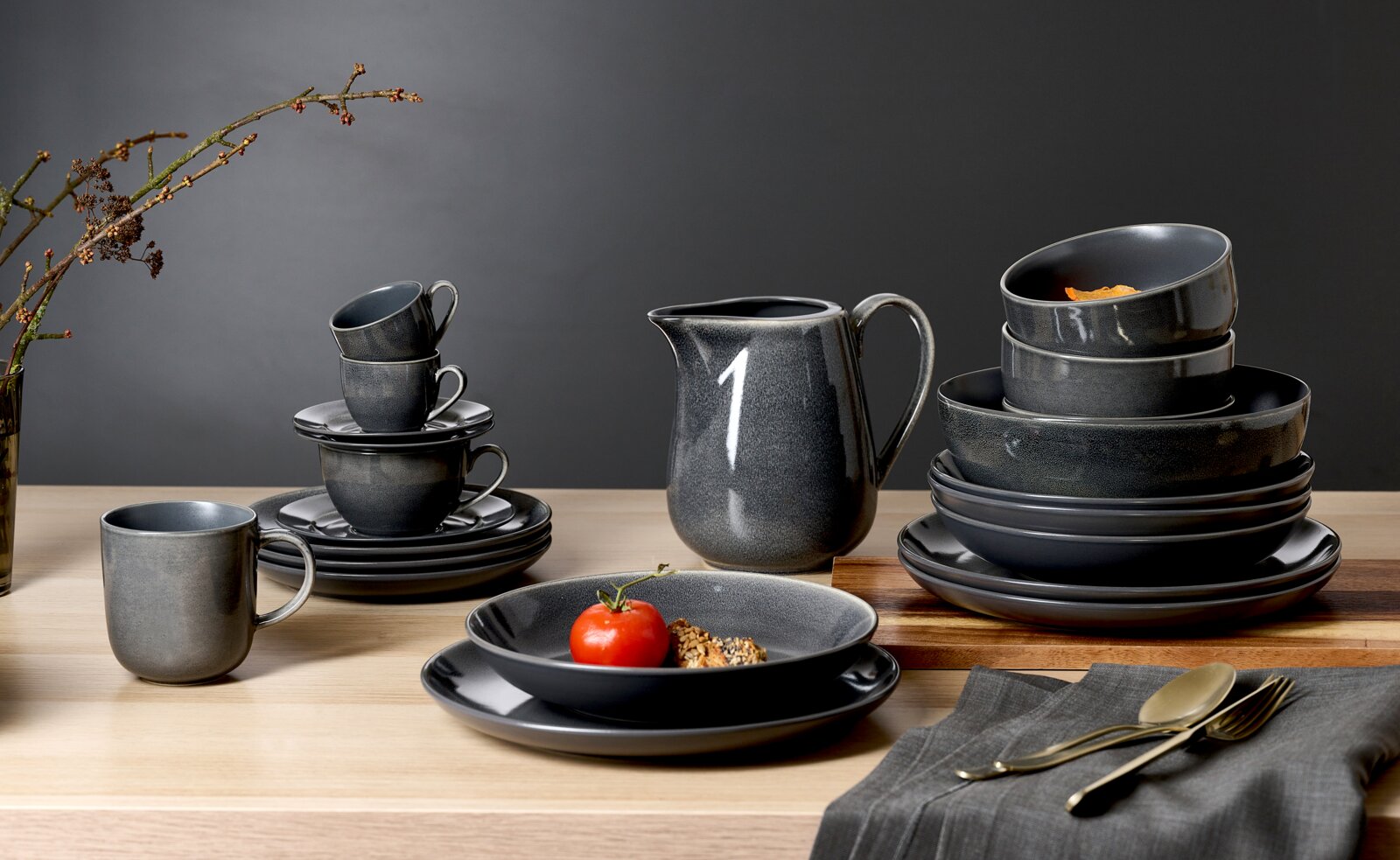 Ritzenhoff & Breker Dessertteller TOLEDO Elegantes, dunkelgraues Geschirrset mit Dessertteller, Tassen und Schalen auf einem Holztisch, seitliche Perspektive.