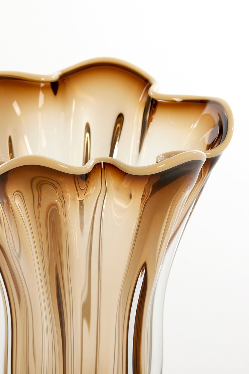 Nahaufnahme einer eleganten Vase mit wellenförmigem Rand und braunen, fließenden Farbverläufen.