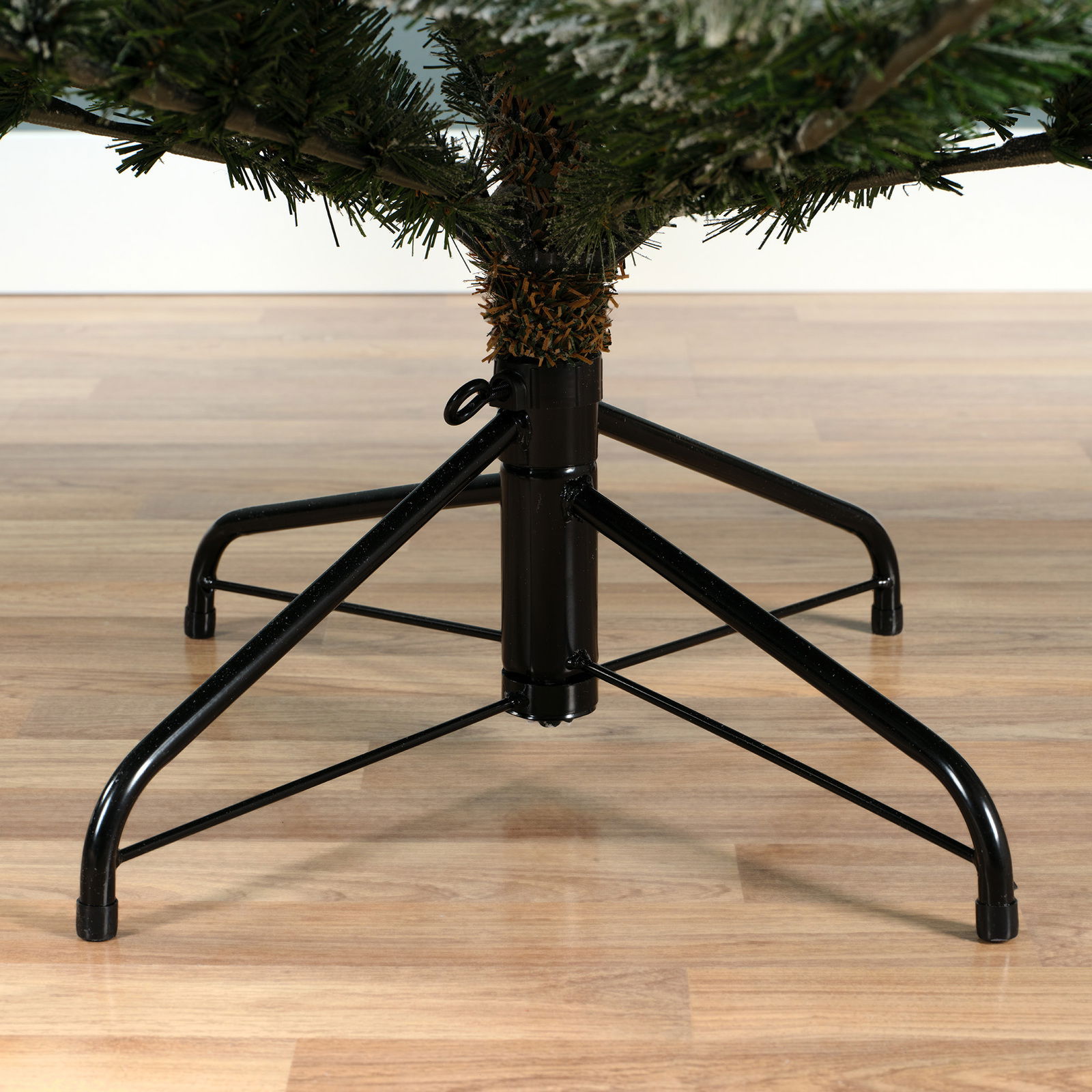 Nahaufnahme eines stabilen Metallständers für einen Weihnachtsbaum auf einem Holzboden, seitliche Perspektive.